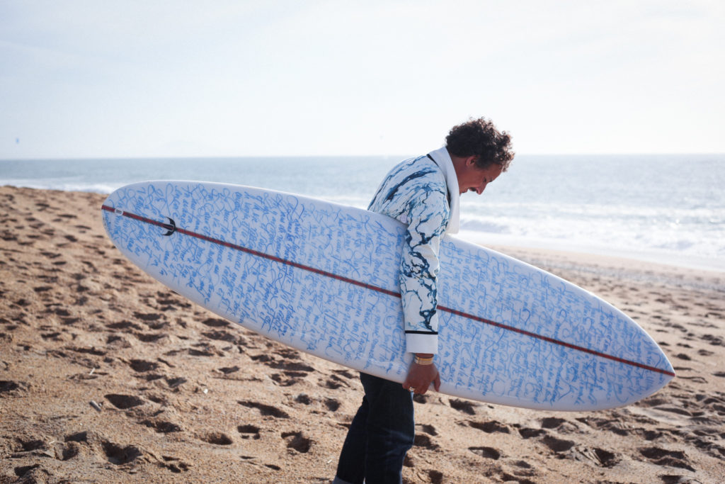 Nicolas Ouchenir tenant une planche surf Duren X Nicolas Ouchenir